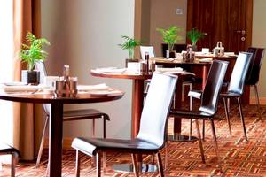 Speisesaal des Malta Marriott Hotel & Spa mit gedeckten Tischen und braunen Stühlen.