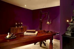 Behandlungsraum im Malta Marriott Hotel & Spa mit violetten Wänden, Buddha-Statue, Tisch und Kerzen