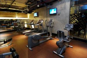 Fitnessstudio im Siam@Siam Design Hotel in Bangkok mit mehreren Laufbändern und Trainingsgeräten.
