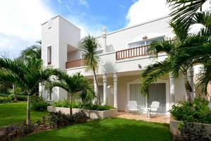 Außenansicht des weißen Hotels Catalonia Playa Maroma mit Balkon, Terrasse und Palmen.
