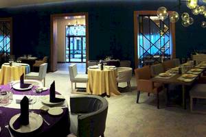Innenansicht des Restaurants im Catalonia Playa Maroma Hotel mit gedeckten Tischen und dekorativen Kronleuchtern.