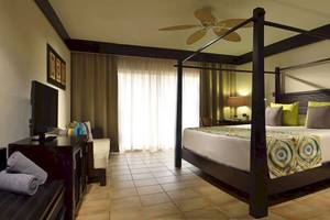 Hotelzimmer im Catalonia Playa Maroma mit Himmelbett, Fernseher, und luxuriöser Einrichtung.
