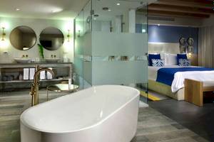 Badezimmer im Catalonia Playa Maroma Hotel mit Badewanne, Spiegelschrank und Doppelbett.