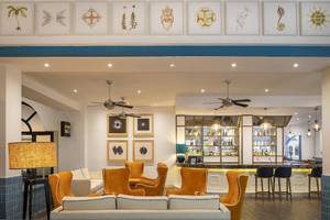 Innenbereich der Bar im Ocean Maya Royale Hotel mit orangefarbenen Sesseln und Theke.