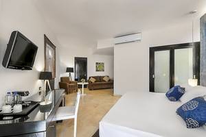 Ein modernes Hotelzimmer mit einem Bett, einem Fernseher an der Wand, einem Schreibtisch und einem kleinen Sofa.
