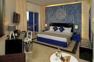Hotelzimmer im Ocean Maya Royale mit Blick auf das Meer, Bett, Schreibtisch und Balkon.