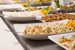 Buffet mit verschiedenen Gerichten im Side Aluna Hotel, darunter Nudeln, Salate und andere Speisen in weißen Tellern.