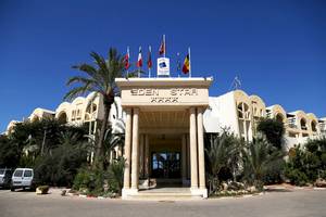 Eingang des Eden Star Zarzis Hotels mit Palme und Flaggen.