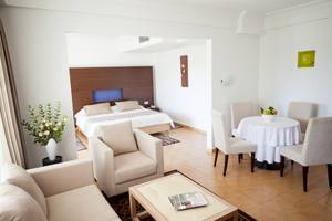 Innenansicht der Suite im El Mouradi Club Kantaoui mit Bett, Wohnzimmer und Essbereich.