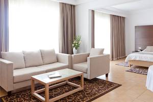 Schlafzimmer im El Mouradi Club Kantaoui Hotel mit einem Bett, Sofas und einem Tisch.