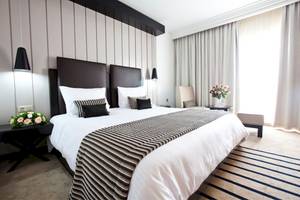 Ein elegantes Hotelzimmer im El Mouradi Palace mit einem Doppelbett, Blumenvase, und modernen Möbeln.