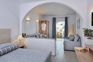 Innenansicht eines Zimmers im Aegean Plaza Hotel mit Bett, Wohnzimmer und Balkon.