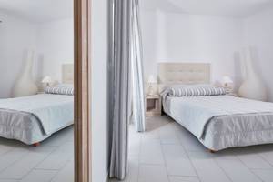 Zwei Schlafzimmer im Aegean Plaza Hotel mit weißen Möbeln und grauen Vorhängen.