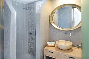 Badezimmer im Aegean Plaza Hotel mit Regendusche und ovalem Spiegel.