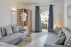 Wohnzimmer im Aegean Plaza Hotel mit zwei Sofas, einem Tisch, einem Kleiderschrank und einem Balkon.