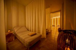 Hotel-Lounge-Bereich im Secrets Lanzarote Resort & Spa mit einem Liegestuhl, Kerzen und einem offenen Durchgang.