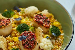 Ein Teller mit Jakobsmuscheln, Brokkoli, Mais und Couscous im Burj Al Arab Jumeirah Hotel.