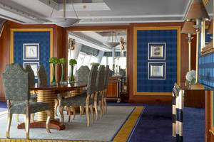 Speisesaal im Burj Al Arab Jumeirah mit blauen Wänden, goldenen Akzenten und einem runden Tisch mit Stühlen.