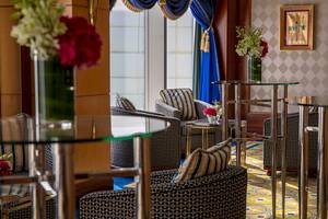 Innenansicht des Burj Al Arab Jumeirah Hotels mit runden Tischen, Stühlen und Blumenvasen.