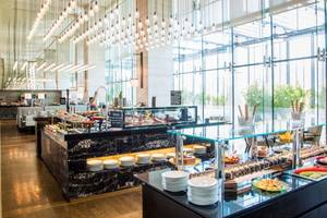 Restaurant im Pullman Dubai Downtown Hotel mit vielen Speisen und hängenden Lampen.