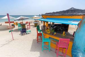 Strandbar im Radisson Blu Resort, Fujairah, mit bunten Stühlen und Tischen.