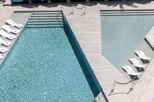Luftaufnahme des Swimmingpools im W Ibiza Hotel mit weißen Sonnenliegen.