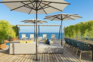 W Ibiza Hotel Terrasse mit Sofa und Sonnenschirmen am Meer