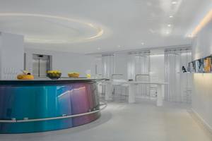 W Ibiza Hotel Innenraum mit Bar, blauer Theke, weißen Stühlen und Tisch.