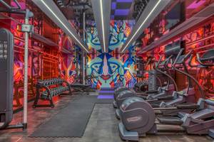 Fitnessstudio im W Ibiza Hotel mit bunten Wänden und Technogym-Geräten.