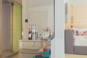W Ibiza Hotelzimmer mit Spiegelschrank, Flaschen und Bett im Hintergrund