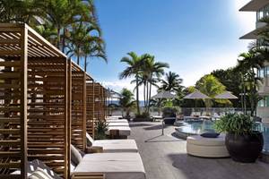 Loungebereich des Victor South Beach Hotels mit Pool, weißen Liegen und Palmen.