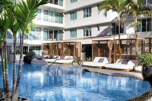 Pool-Lounge-Bereich des Victor South Beach Hotels mit weißen Sonnenliegen und braunen Holzschirmen.