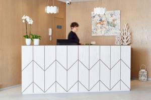 Rezeption des Universal Aparthotel Elisa mit weißem Schalter und Pflanzen.