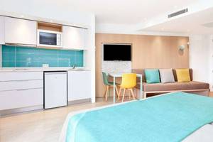 Innenansicht eines Zimmers im Universal Aparthotel Elisa mit Küche, Esstisch und Schlafbereich.