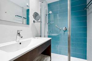 Ein Badezimmer mit blauen Fliesen, einer Duschkabine und einem Waschbecken im Universal Aparthotel Elisa.