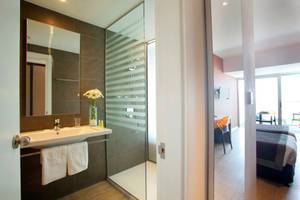 Badezimmer im Faros Hotel Ayia Napa mit Dusche, Spiegel und Waschbecken.
