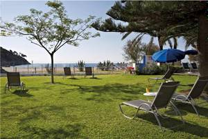 Gartenbereich des Castell Royal Hotels mit Sonnenliegen und Sonnenschirmen in der Nähe des Strandes