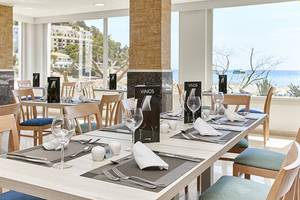 Innenansicht des Restaurants im Castell Royal Hotel mit Blick auf das Meer und der Terrasse.