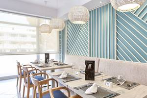 Innenansicht des Restaurants im Castell Royal Hotel mit blauen Wänden und Holztischen.