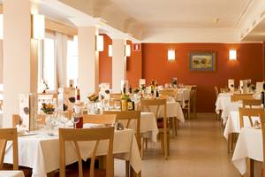 Innenansicht des Restaurants im Bikini Hotel mit geräumigen Tischen und Stühlen, dekorativ beleuchteten Wänden und kunstvollen Wandgemälden.