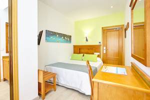 Ein helles Hotelzimmer im Laguna Hotel mit Bett, Schreibtisch und Dekoration.