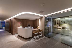 Lobby und Rezeption des Faros Hotel Ayia Napa mit modernem Design, hölzernen Wänden und einem Schreibtisch.