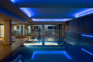 Das Fitnessstudio des Faros Hotel Ayia Napa mit einem Schwimmbecken und blauer Beleuchtung.