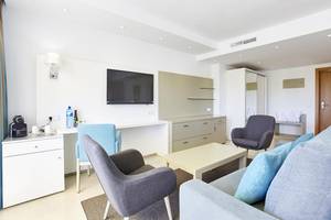 Wohnbereich im Lido Park Hotel mit Fernseher, Schreibtisch, Stühlen und Sofa.