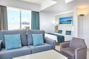 Innenansicht eines Hotelzimmers im Lido Park Hotel mit einem Bett, Sofa, Tisch und Aussicht.