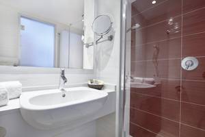 Badezimmer des Perla Hotels mit einem Spiegel und einer roten gefliesten Dusche.