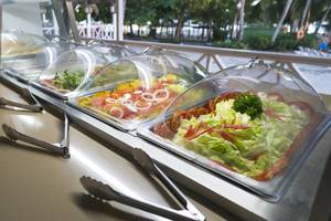 Buffet-Tisch im Coral Costa Caribe Beach Resort mit Salat, Tomaten und anderen Gemüsesorten.
