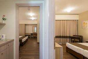 Innenansicht des Zimmers im Sandy Beach Hotel auf Kos mit zwei Betten, Tisch, Stuhl und Dekor.