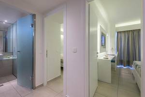 Innenansicht eines Zimmers im Sandy Beach Hotel in Kos mit moderner Einrichtung, Schreibtisch und Bett.