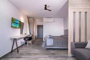 Innenansicht eines Zimmers im Sandy Beach Hotel auf Kos mit Bett, Schreibtisch, Fernseher und Klimaanlage.